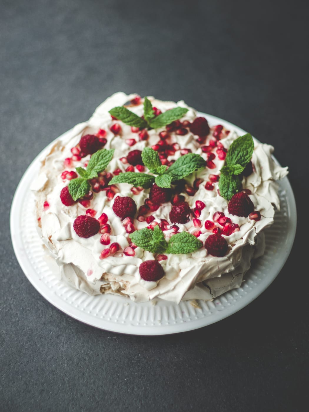 A pavlova with berries and mint.