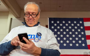A supporter checks his phone as he attends the Caucus Night Celebration event for Democratic presidential candidate Vermont Senator Bernie Sanders in Des Moines, Iowa, on February 3, 2020.