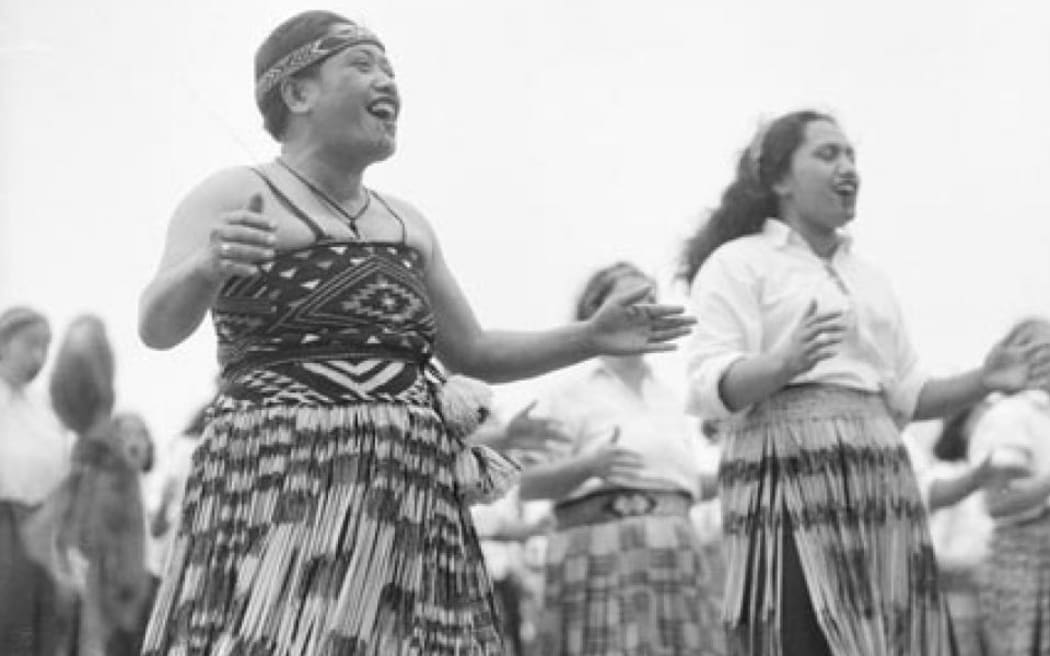 Māori wahine wearing piupiu (skirts) smile while performing a waiata.