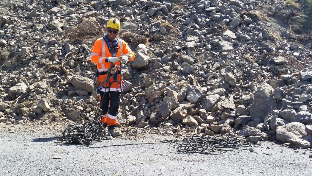 A member of an abseiling crew tidies his rope after descending a large landslide south of Kaikoura.