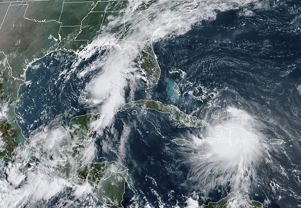 A satellite image shows Tropical Storm Laura moving over Haiti and the Dominican Republic in the Caribbean as a second tropical storm, named Marco (upper left) moves into the Gulf Coast.