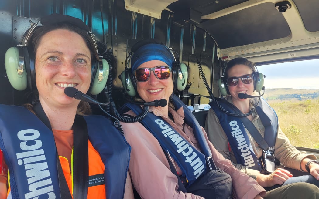 Doc biodviersity ranger Allanah Purdie, herpetologist Marieke Lettink, and biodiversity ranger Kaitlyn Leeds in a helicopter en route to Motunau Island