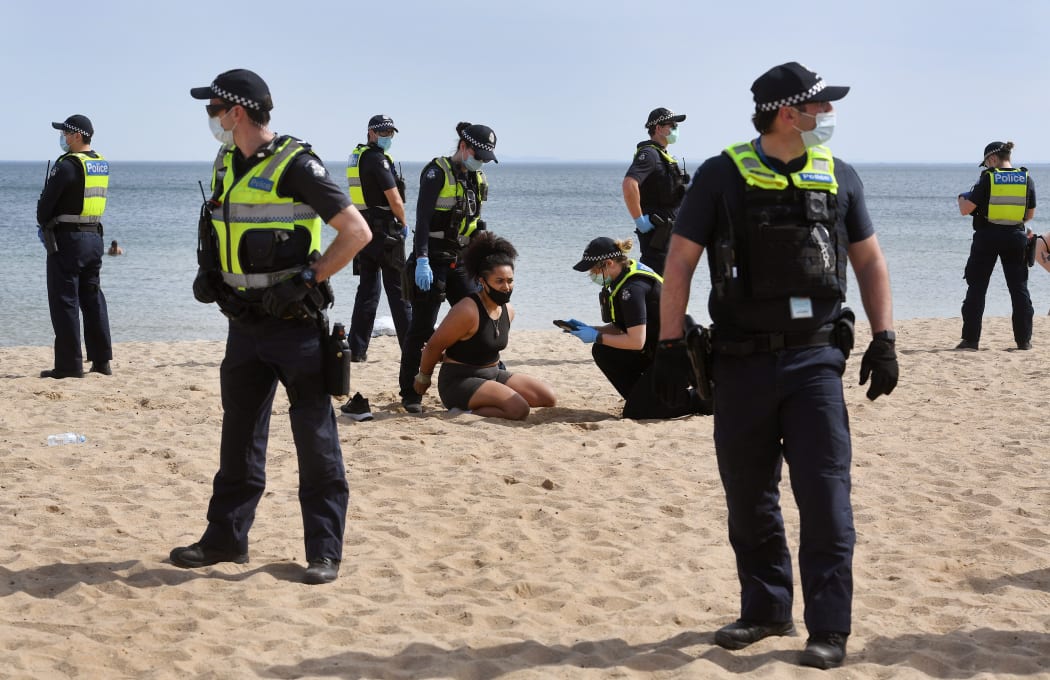 Police surround a protester at an anti-lockdown protest as they detain her at Elwood Beach in Melbourne in the weekend.