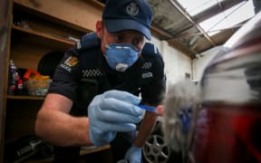 A policeman dusting a car with fingerprint powder