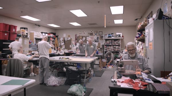 Several Missouri prisoners working on quilt projects in a sewing room packed with fabric, in the Netflix documentary The Quilters.