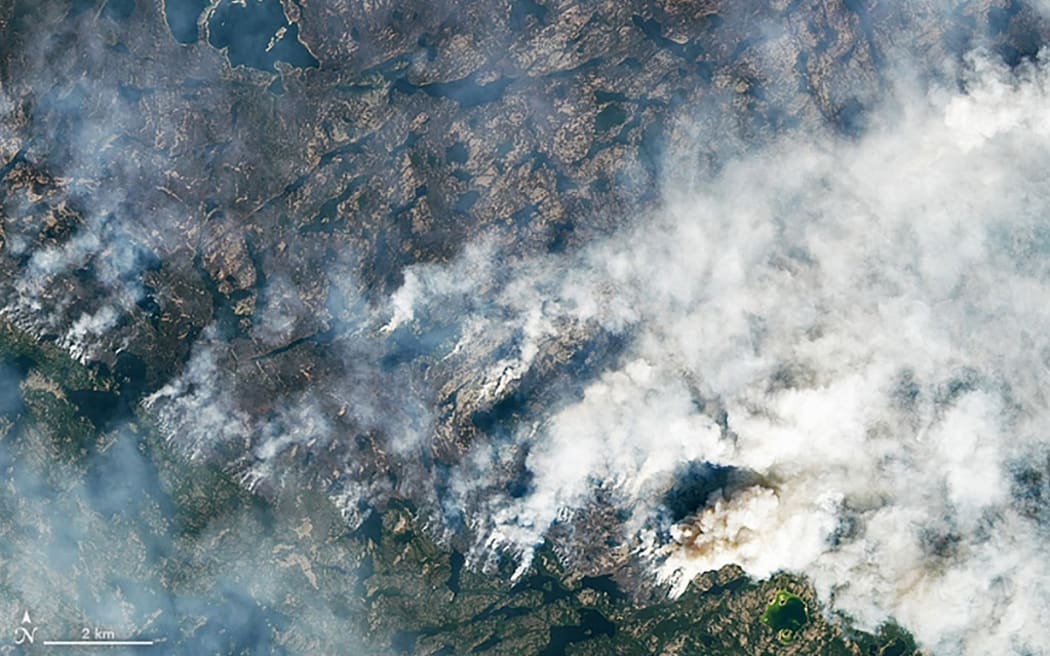 This handout satellite image courtesy of NASA Earth Observatory taken on August 16, 2023 shows wildfires burning northeast of Yellowknife, Northwest Territories, Canada. Thousands ordered to flee wildfires advancing on one of the largest cities in Canada's far north started leaving on emergency evacuation flights August 17, 2023, as convoys snaked south to safety on the only open highway. The order late August 16 to evacuate Yellowknife in the Northwest Territories marked the latest chapter of a terrible summer for wildfires in Canada, with tens of thousands of people forced to leave their homes and vast swaths of land scorched. (Photo by NASA Earth Observatory / AFP) / RESTRICTED TO EDITORIAL USE - MANDATORY CREDIT "AFP PHOTO / NASA Earth Observatory)" - NO MARKETING NO ADVERTISING CAMPAIGNS - DISTRIBUTED AS A SERVICE TO CLIENTS