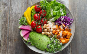 A vibrant bowl of salad vegetables, including avocado and chickpeas