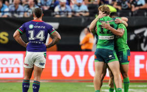 A dejected Dylan Walker of the Warriors looks on as Canberra Raiders celebrate a try.