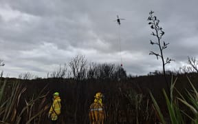 A helicopter supporting ground crews to extinguish hotspots at the Tiwai Road fire in Awarua this morning.