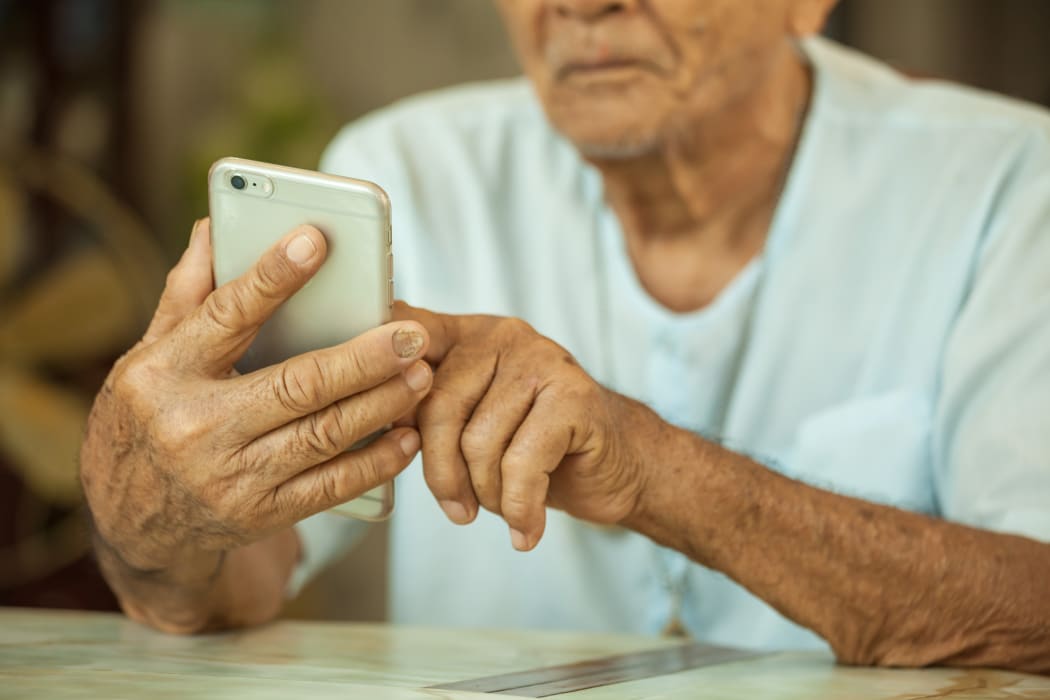 Happy asian senior man using the mobile phone at home