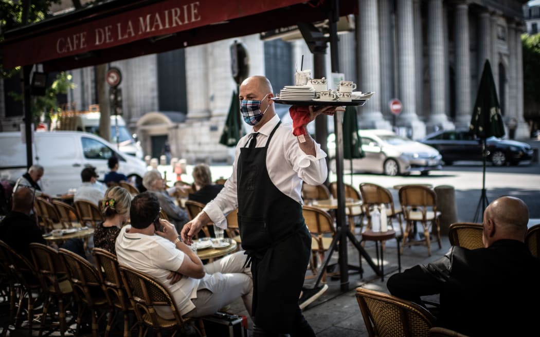 A masked waiter works at the terrace of the Cafe de la Mairie on the Place Saint-Sulpice in Paris on June 2, 2020, as cafes and restaurants reopen in France.