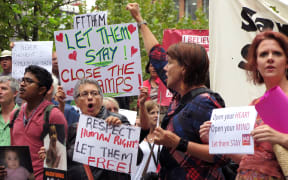 People hold up placards at a protest outside an immigration office in Sydney on 4 February 2016.