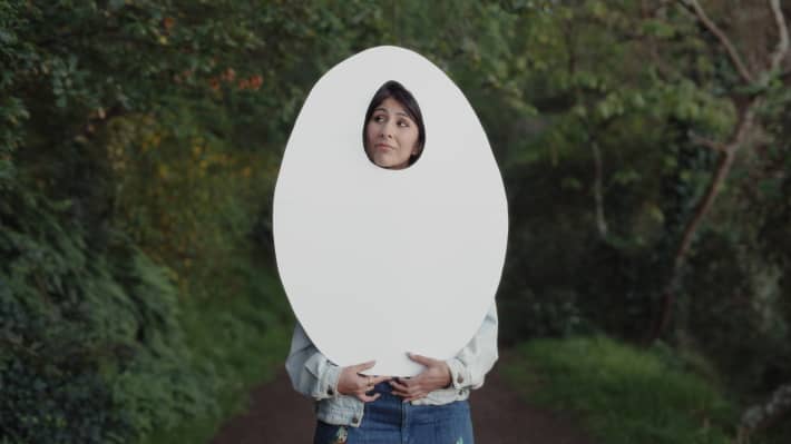 Director Shamin Yazdani holds up a cardboard cutout of an egg shape.
