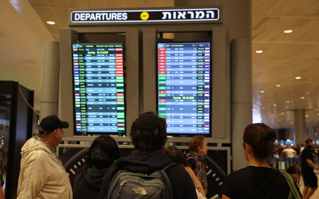 Passengers look at a departure board at Ben Gurion Airport near Tel Aviv, Israel, on October 7, 2023, as flights are canceled because of the Hamas surprise attacks. The conflict sparked major disruption at Tel Aviv airport, with American Airlines, Emirates, Lufthansa and Ryanair among carriers with cancelled flights. (Photo by GIL COHEN-MAGEN / AFP)