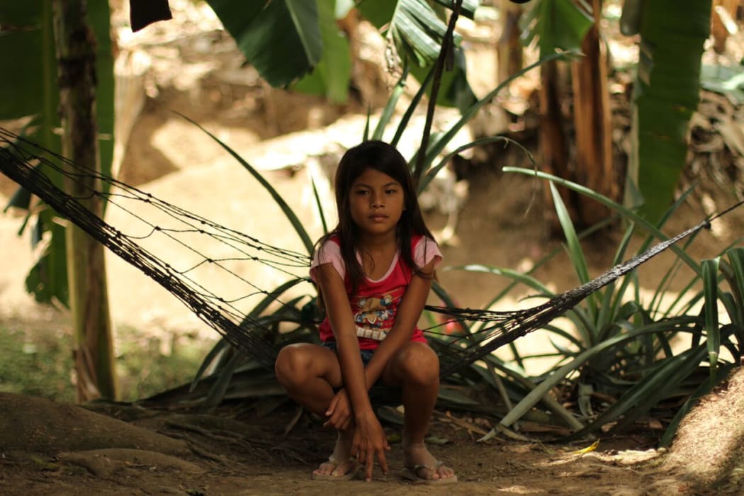 A girl plays in the plantation, surrounded by banana trees. Parents fear their children will suffer health effects from the sprays.