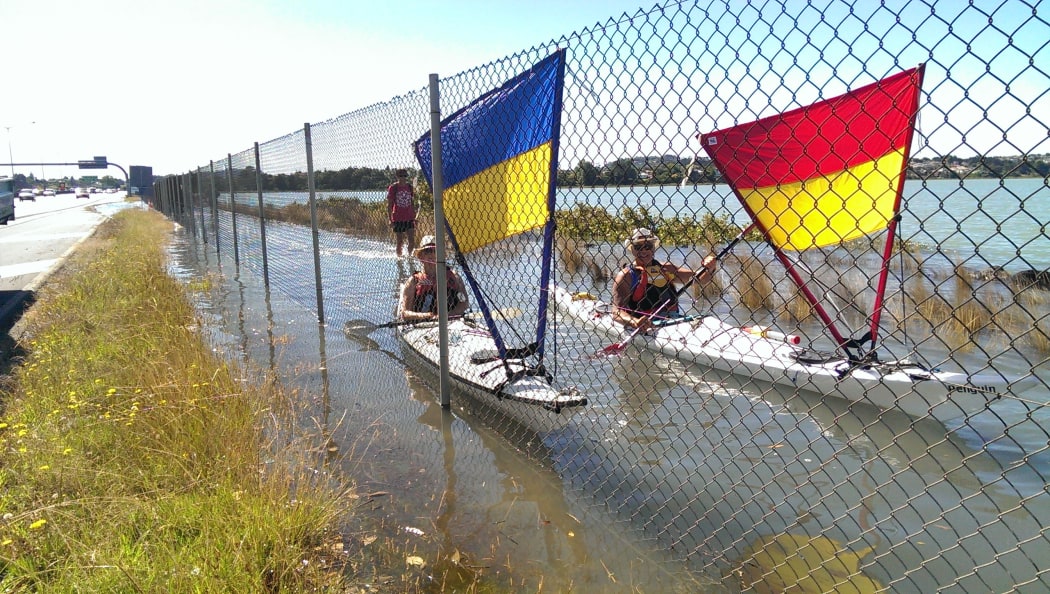 Kayakers taking advantage of the high tide covering the cycleway along Auckland's North Western motorway.