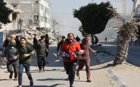 Palestinians rush an injured girl away from the site of Israeli strikes on a makeshift displacement camp in central Gaza City on March 23, 2025. Israel on March 18 resumed military operations in the Gaza Strip after a period of relative calm, since a January 19 ceasefire with Hamas paused more than 15 months of war, citing deadlock in indirect negotiations on next steps in the truce after its first stage expired earlier in March. (Photo by Omar AL-QATTAA / AFP)