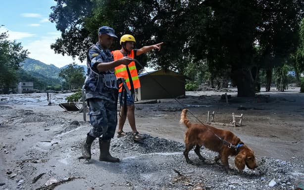 A member of the security forces and his sniffer dog search for survivors following flash floods at Trishuli in Nepal's Nuwakot district on August 27, 2026. Rescue teams scoured devastated zones on August 27 for more than 1,300 people missing a day after flash floods and landslides along the Nepal-Tibet border killed at least 180, sweeping away entire villages. (Photo by Prakash MATHEMA / AFP)