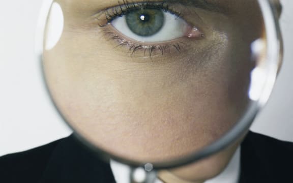 Portrait woman posing, with magnifying glass in front of her eye. (Photo by Double Touch / Photononstop / Photononstop via AFP)