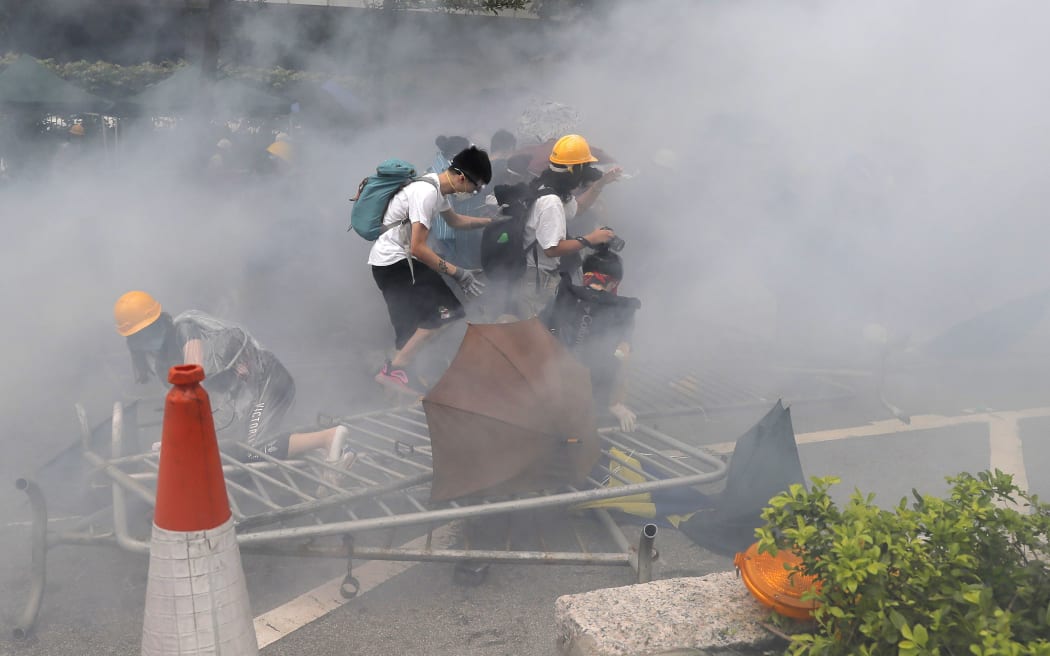 Protesters react to a cloud of tear gas near the Legislative Council in Hong Kong, Wednesday, June 12, 2019.