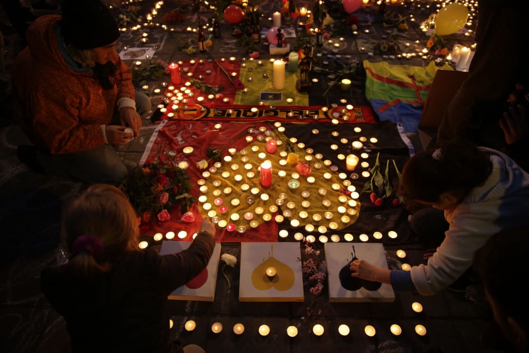 People light candles in tribute to victims at a makeshift memorial in front of the stock exchange at the Place de la Bourse in Brussels on March 22, 2016.