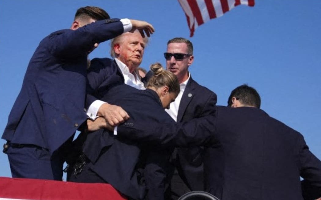 This video screenshot shows former US President Donald Trump being helped off the stage at a rally in Butler, Pennsylvania, on 13 July, 2024.