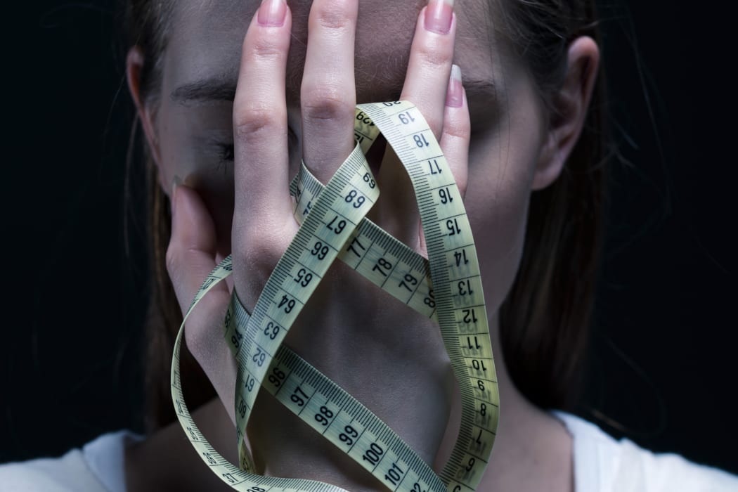 Anorexic girl covering her face with a centimeter