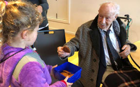 Madison Webb baked Anzac biscuits for veterans at the RSA in Christchurch.
After the dawn service she gives one to 106-year-old veteran, sergeant Bill Mitchell, who fought in the Pacific during his time in the defence force.