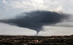 A plume of dark smoke rises over the northern Gaza Strip during Israeli bombardment from southern Israel on December 27, 2023 amid continuing battles between Israel and the Palestinian militant group Hamas. (Photo by JACK GUEZ / AFP)
