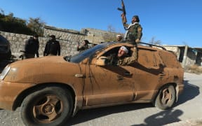 Anti-government fighters celebrate in a street in Maaret al-Numan in Syria's northwestern Idlib province on November 30, 2024.