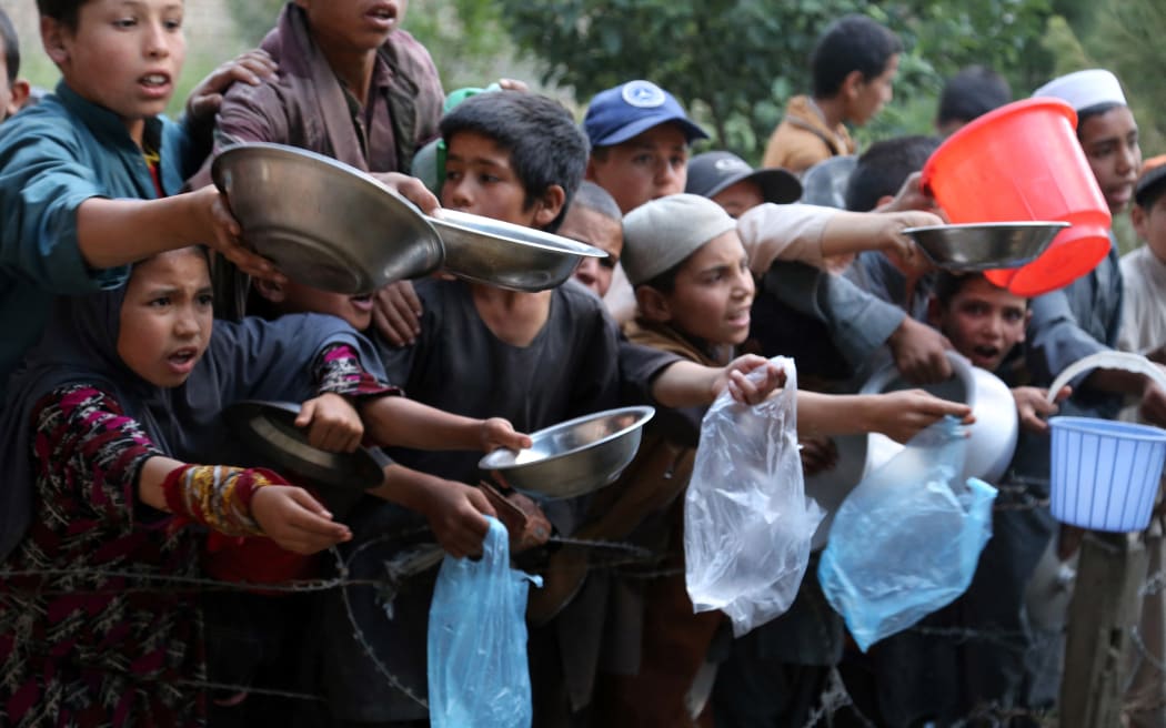 In this photograph taken on June 6, 2016, young children wait as an Afghan man distributes food for the needy during the first day of the Islamic holy month of Ramadan in Ghazni province. Across the Muslim world, the faithful fast from dawn to dusk and strive to be more pious during the holy month, which ends with the Eid holiday.