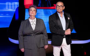 Anne Hegerty and Paul Henry stand confidently in front of a neon TV set.