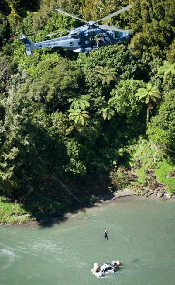 An NH90 Air Force helicopter winches a car from the Mohaka River.