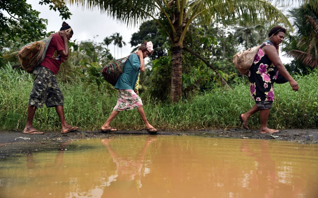 PNG women carrying wood in the town of Kerema.