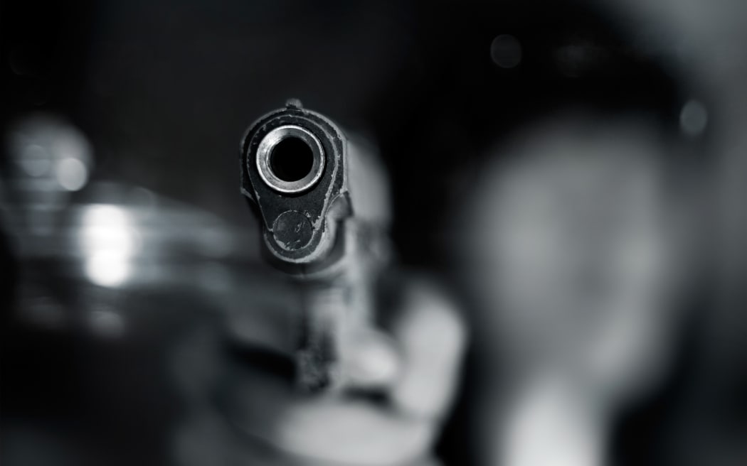 Black and white, woman pointing a old gun to front with one Hand on dark background
