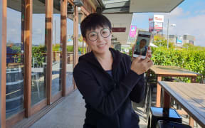 Rita Li holding up a photo of her two-year-old daughter Catherine