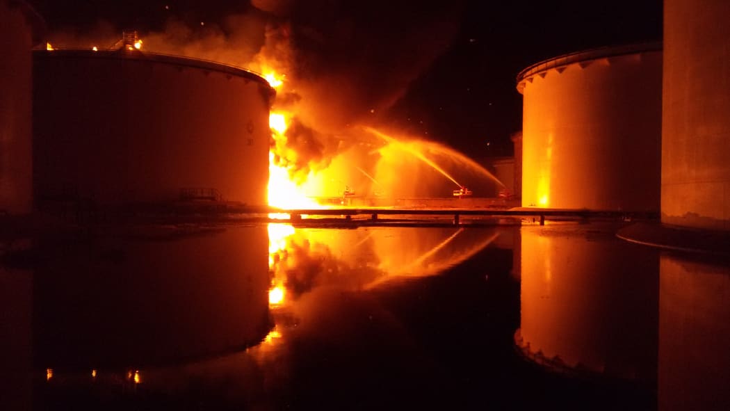 A huge fire near Tripoli airport in Libya has spread to a second fuel tank, despite firefighters' efforts.