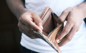 A person in a white t-shirt showing an empty wallet.