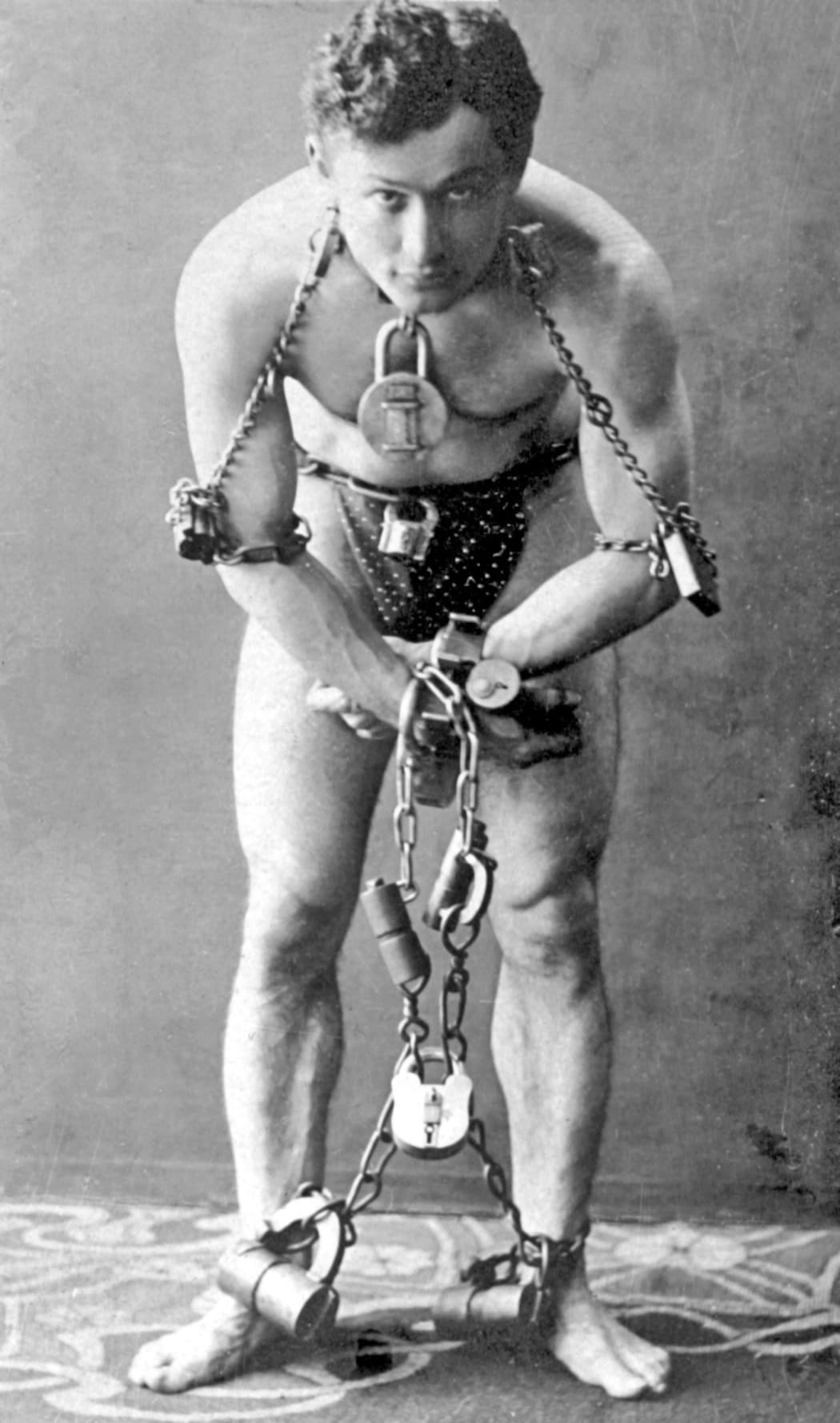 Harry Houdini, full-length portrait, standing, facing front, in chains