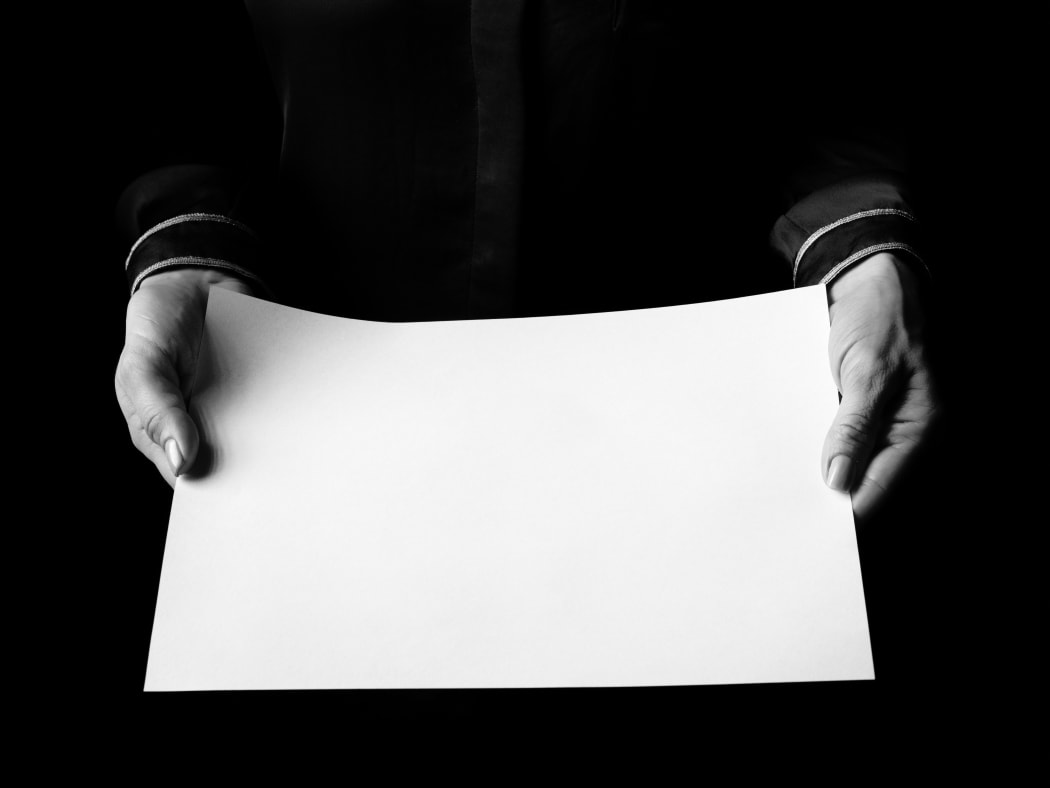 Black Mania. female hands isolated on black showing blank paper sheet