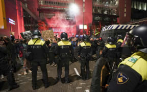 Riot police officers face protesters as they gather in the Hague,during a press conference of Dutch Prime Minister held to announce new Covid-19 restrictions.