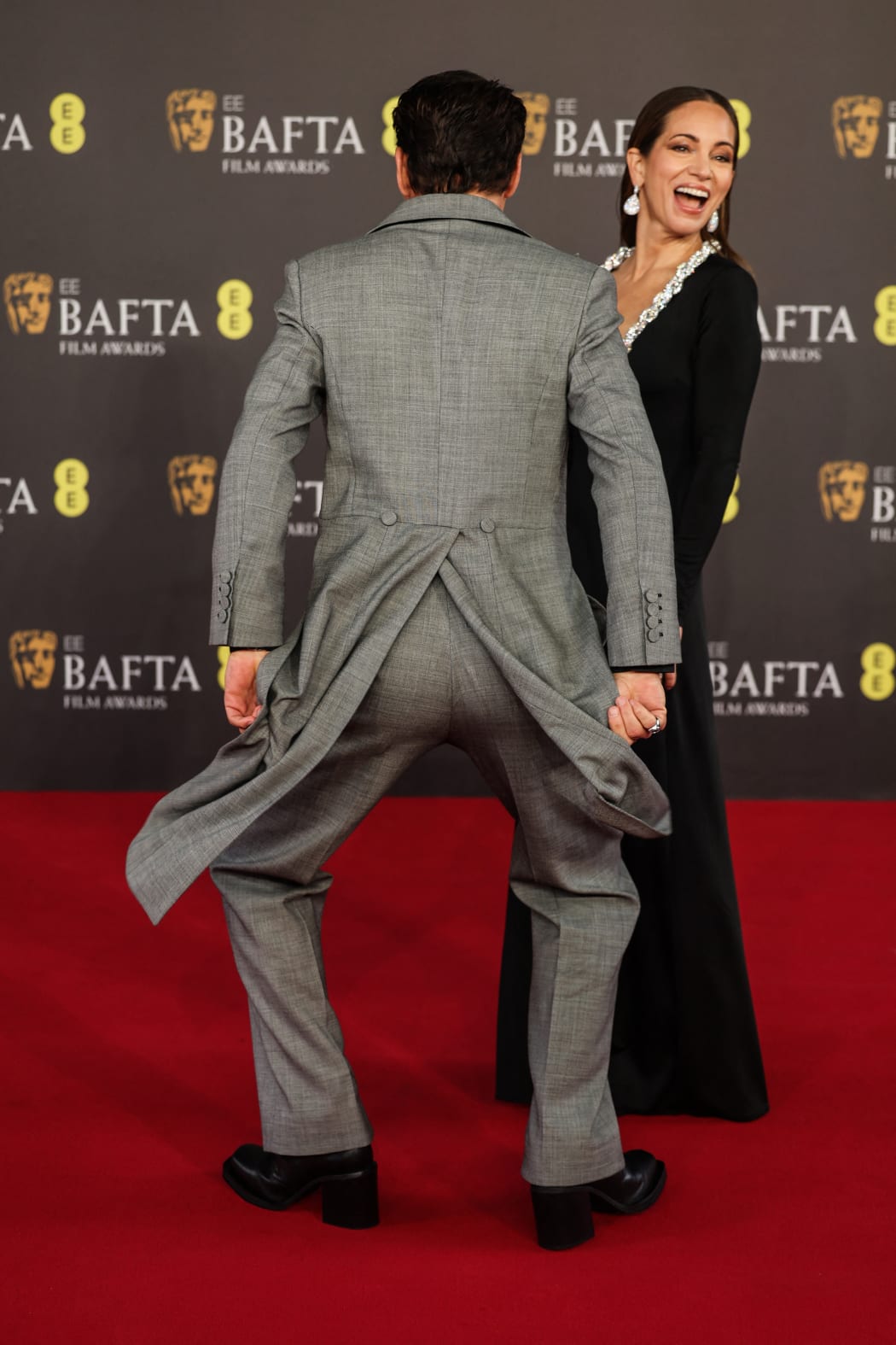 US actor Robert Downey Jr dances whilst US film producer Susan Downey (R) reacts on the red carpet upon arrival at the BAFTA British Academy Film Awards at the Royal Festival Hall, Southbank Centre, in London, on February 18, 2024. (Photo by Adrian DENNIS / AFP)