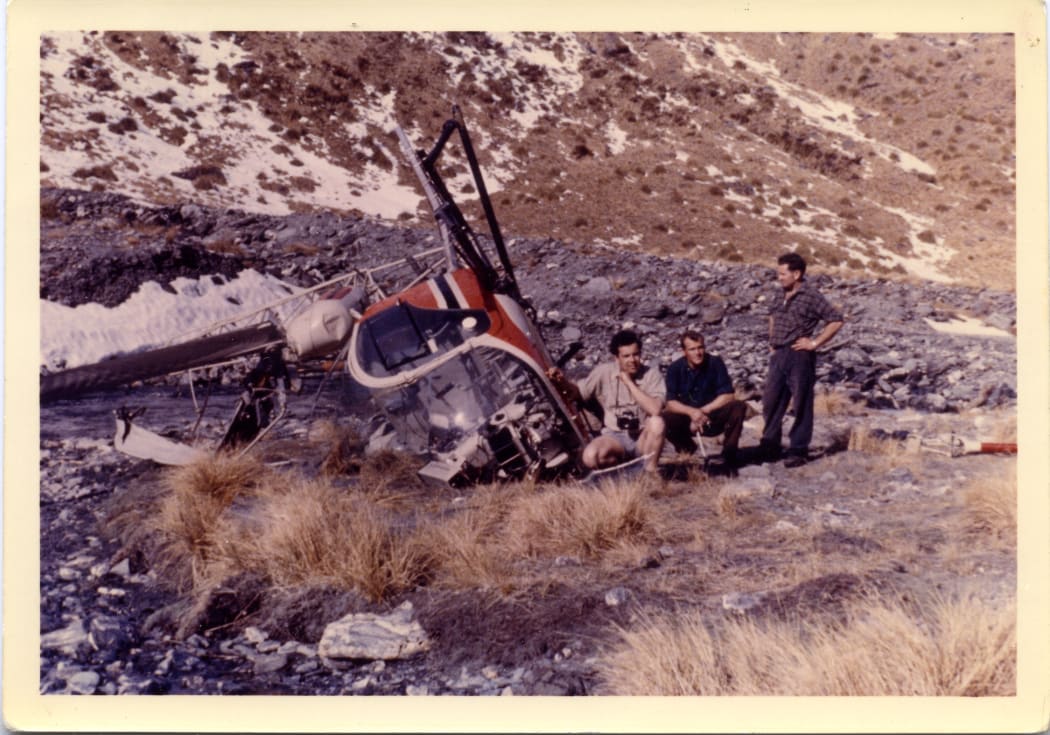 Men standing beside a crashed helicopter