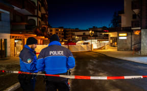 Police control access to the street where a fire ripped through a crowded bar during New Year's Eve celebrations in the Alpine ski resort town of Crans-Montana on January 1, 2026. Several dozen people are presumed dead and around 100 injured after a fire ripped through a crowded bar in the luxury Swiss ski resort of Crans-Montana, Swiss police said on January 1, 2026. Police, firefighters and rescuers rushed to the popular resort, which is set to host the Ski World Cup from January 30, after the fire broke out in the early hours of New Year's Day. (Photo by MAXIME SCHMID / AFP)