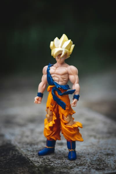 An action figure with rigid yellow hair wears ripped orange pants.