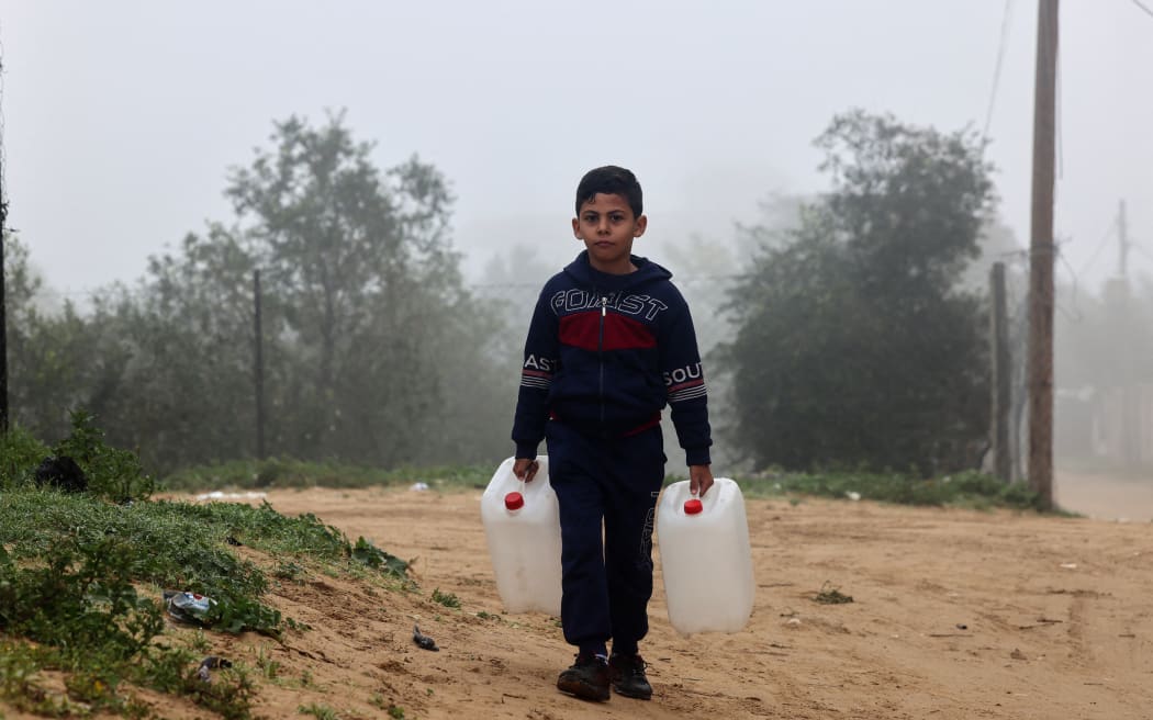 A child carries empty jerry cans on his way to fetch water on 9 February. (Photo by Mohammed ABED / AFP)