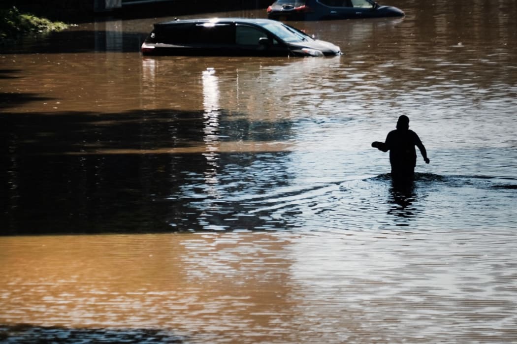 NEW YORK CITY - SEPTEMBER 02: A man walks through a flooded Major Deegan Expressway in the Bronx as dozens of cars and trucks sit abandoned following as night of heavy wind and rain from the remnants of Hurricane Ida on September 02, 2021 in New York City.