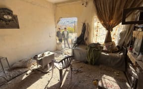 Two youth inspect the site of an Israeli military operation in the southern Syrian village of Beit Jin on 28 November, 2025.
