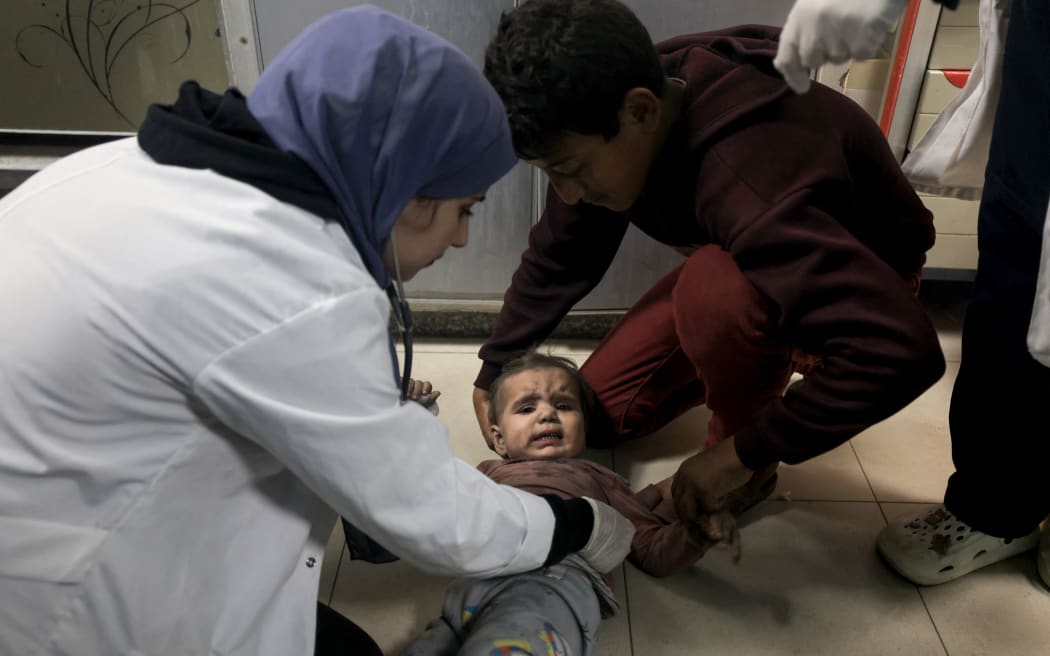 EDITORS NOTE: Graphic content / A medic checks a Palestinian child from the Baraka family brought into Nasser Hospital in Khan Yunis, following Israeli air strikes that hit their building in the southern Gaza Strip city on November 13, 2023. Israel is facing intense international pressure to minimise civilian suffering amid a massive air and ground operation that Hamas authorities say has already killed more than 11,000 people, including thousands of children. The military campaign came after Hamas fighters broke through the militarised border with Israel on October 7, killing around 1,200 people, mostly civilians, and taking about 240 people hostage, according to the most recent Israeli figures. (Photo by Mahmud HAMS / AFP)