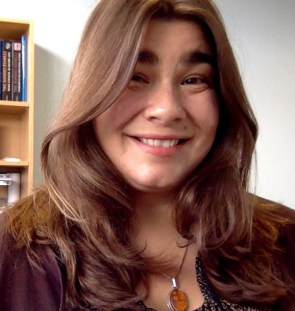 A portrait headshot photo of Sara. Her hair is down and she is smiling.